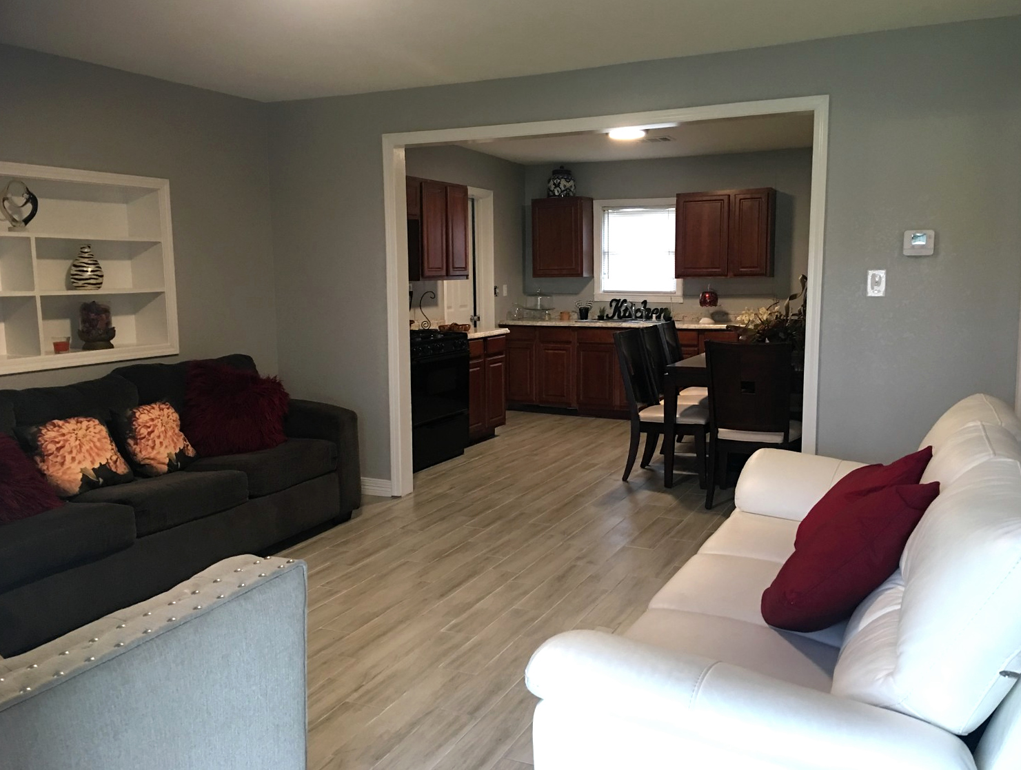 Completed gray living room and kitchen renovation with wood-look flooring and white trim